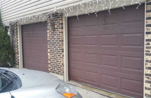 two brown garage doors on brick garage before