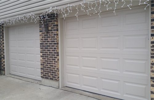 two white garage doors on brick garage after