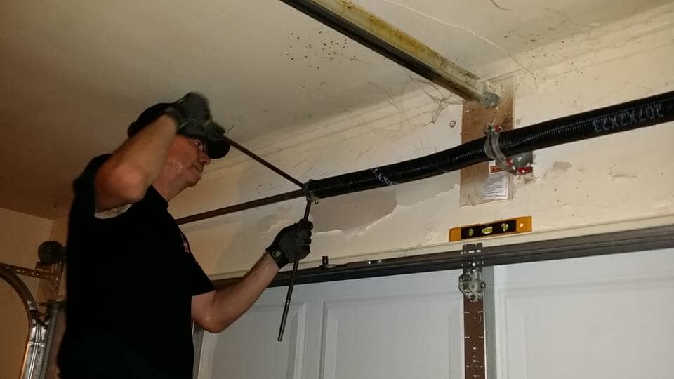 man replacing springs on garage door